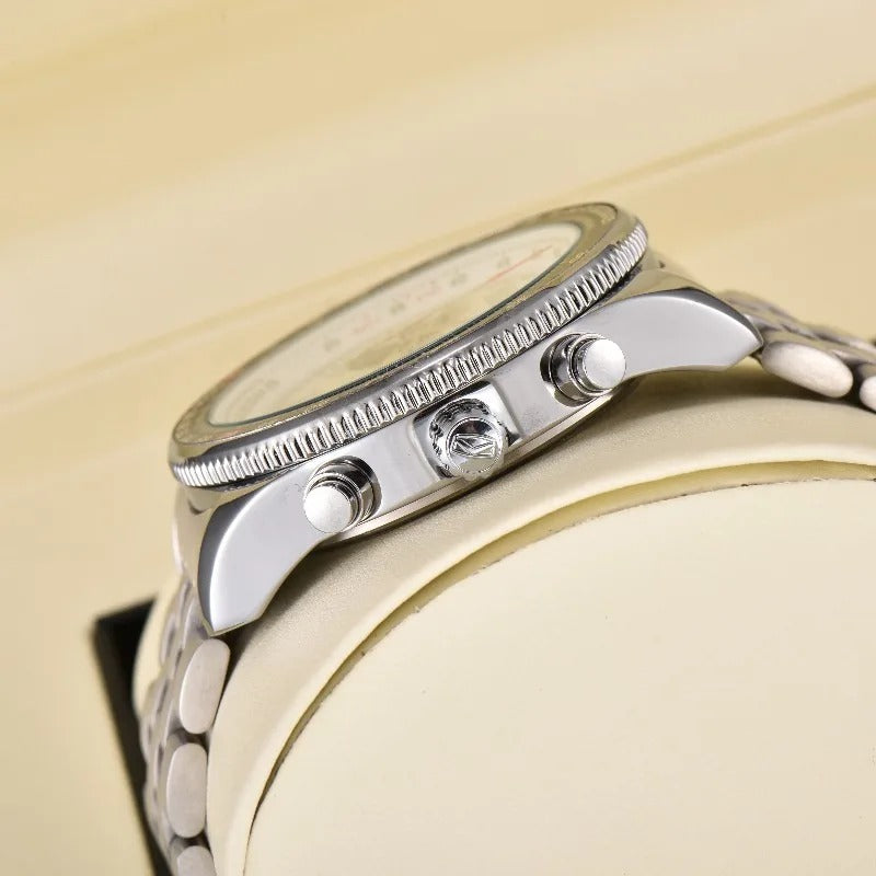 Photograph of a silver chronograph watch with a knurled bezel three pushers and a metal link bracelet displayed on an off-white watch stand