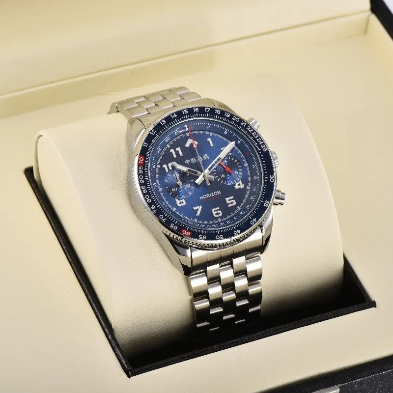 A silver-toned stainless steel men's chronograph wristwatch with a deep blue dial, white Arabic numerals, intricate subdials, and red bezel accents, featuring Chinese characters and "HORIZON" branding, resting in a light cream display box